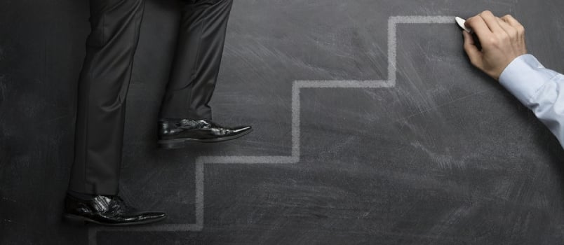 A Helping Hand, Businessman Climbing the Career Steps Drawn on a Black Chalkboard