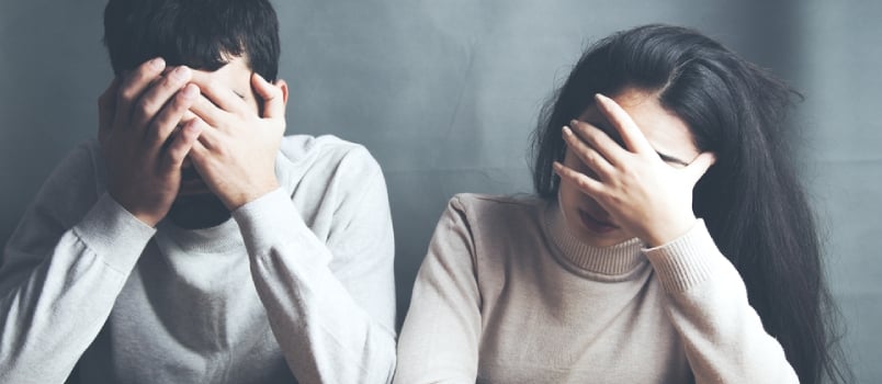 Sad Young Couple Sitting in Table on Dark Background