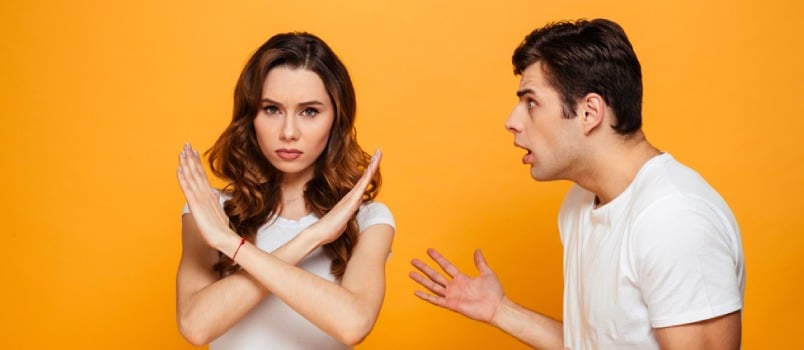 Displeased Man Screaming on His Girlfriend Which Showing Stop Gesture and Looking at the Camera Over Yellow Background