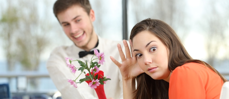 Disgusted Woman Rejecting a Geek Boy Offering Flowers in a Blind Date in a Coffee Shop Interior