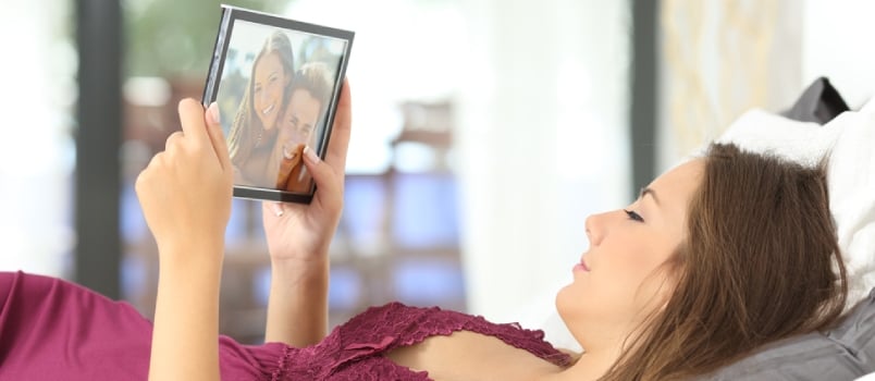 Longing Woman Looking a Picture of Her Boyfriend in a Frame on the Bed at Home