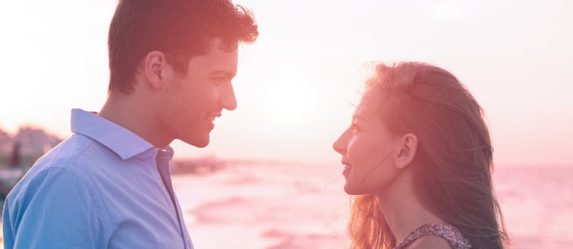Young Couple Face to Face Holding Hands Each Other Standing on the Beach Shore at Sunset