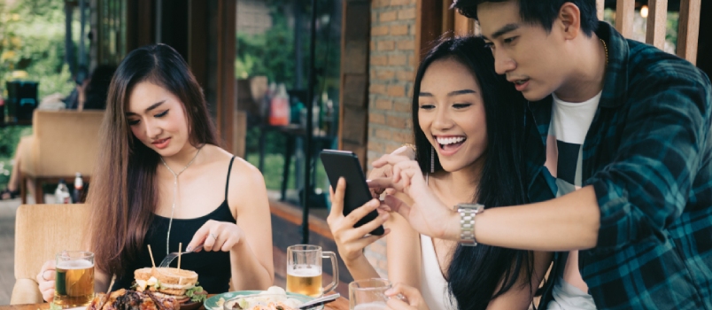 Asian Single Woman Envious With Love Couple Doing Take Selfie at Restaurant.