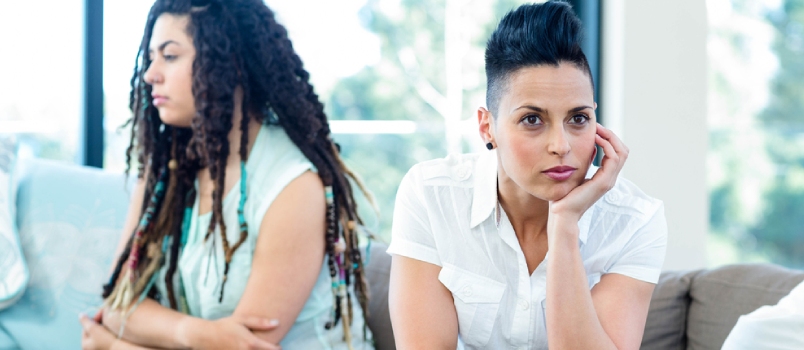Unhappy Lesbian Couple Sitting on Sofa in Living Room