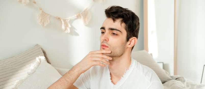 Man sitting on a bed feeling sad