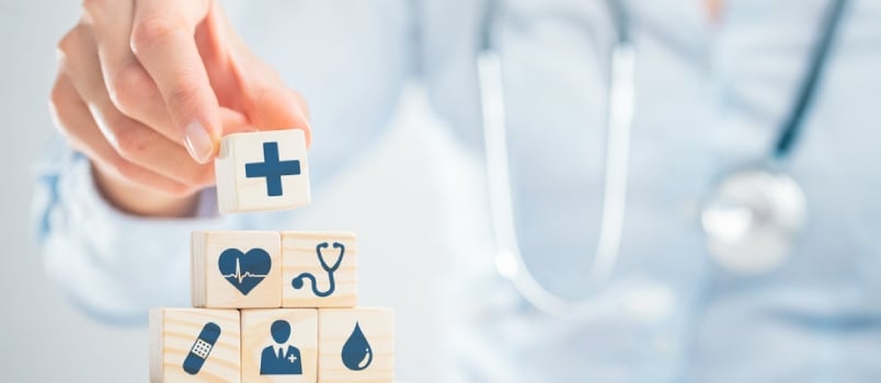 Hand Arranging Wood Block With Healthcare Medical Icon. Health Insurance - Concept.