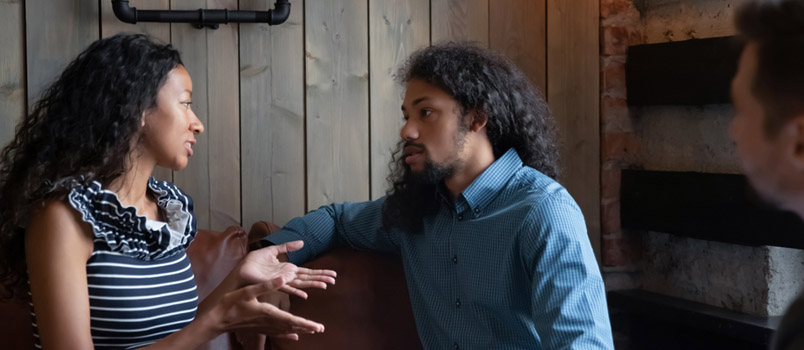 Young Couple Sit on Couch in Coffee Shop for Psychological Therapy With Male Counselor
