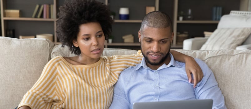 Couple working on the laptop while sitting together in their room