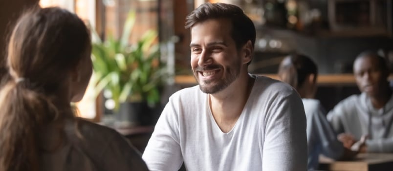 Happy Millennial Man Meeting in Cafe With Young Woman Enjoying Coffee and Talk Together