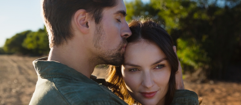 Young Man Kissing Woman on Landscape