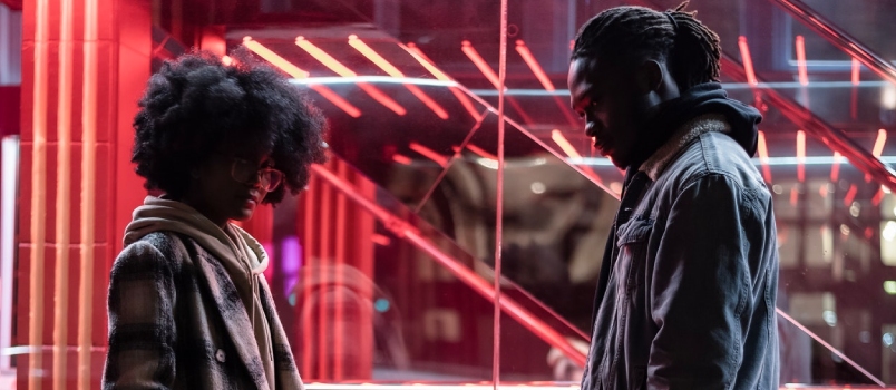Side View Full Body of Offended African American Couple Standing With Hands in Pockets Near Glowing Lights Behind Glass Wall