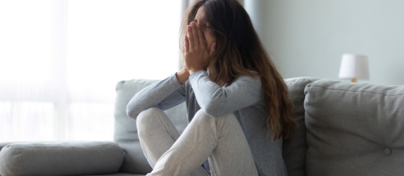 Full Length Desperate Grieving Millennial Biracial Woman Sitting on Couch at Home