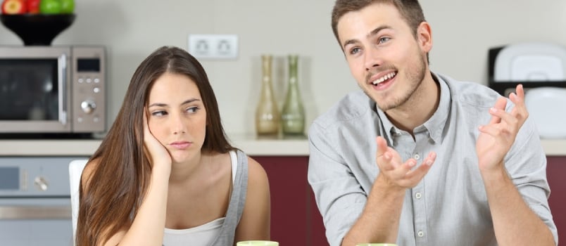 Bored Wife Hearing Her Husband Talking During Breakfast in the Kitchen at Home