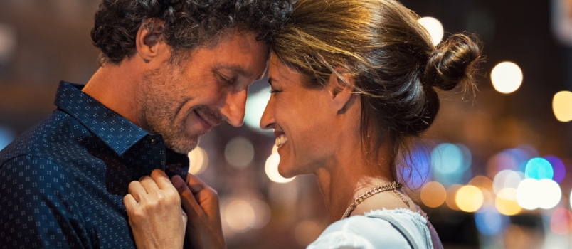 Happy Husband and Smiling Wife Embracing Touching Head to Head on City Street at Night.