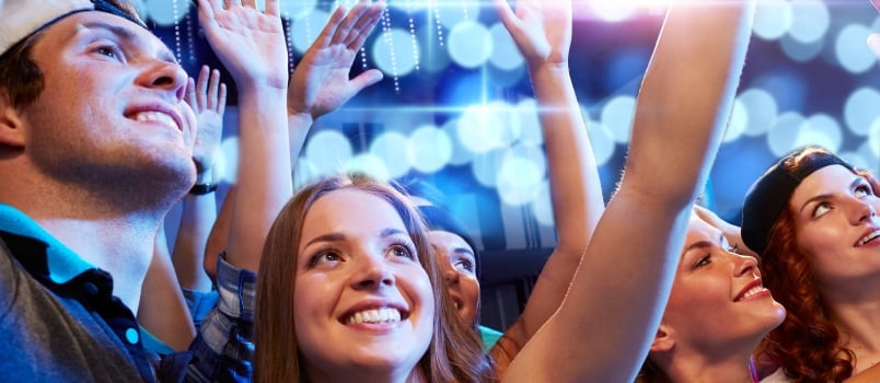 Smiling Friends Waving Hands at Concert in Club