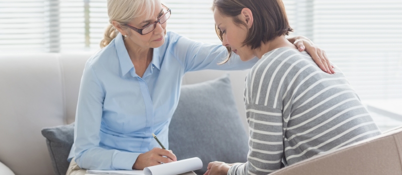 Therapist Comforting Woman on Sofa at Home