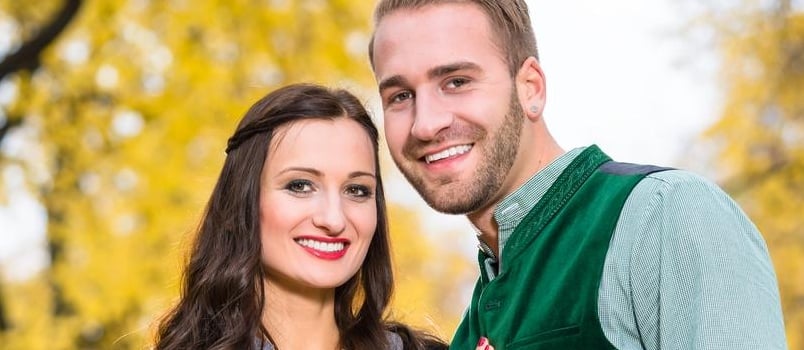 Man and Woman Wearing Bavarian Tracht, in Close Position, Standing in Front of an Alley in Fall