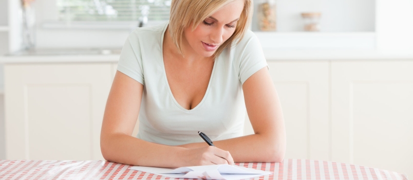 Woman Sitting at a Kitchen Table Writing a Letter