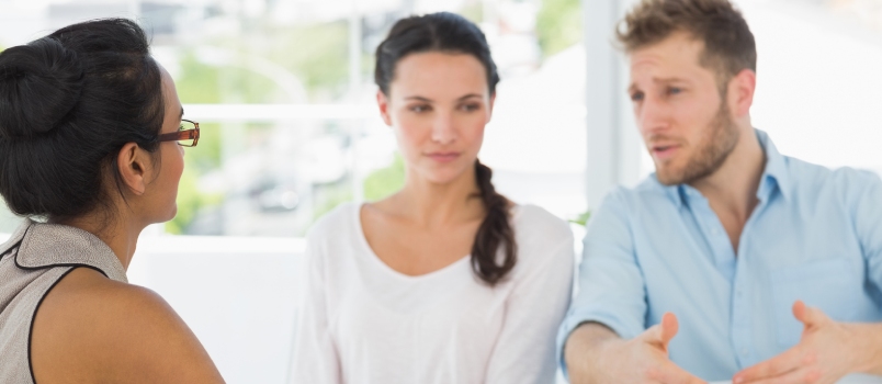 Therapist Speaking With Couple Sitting at Desk in Therapists Office