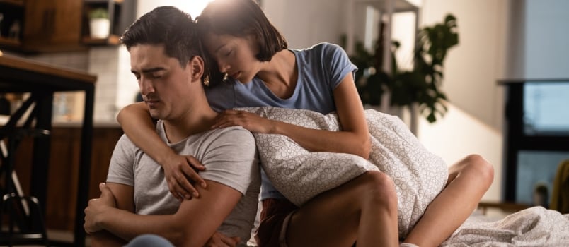 Young Tender Husband Hugging His Wife, Loving Man Embracing Woman Gently and Tightly Sitting on Couch at Home