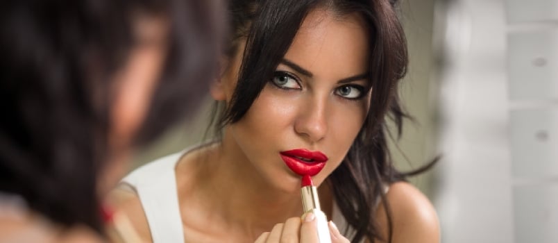 Beautiful woman applying red lipstick