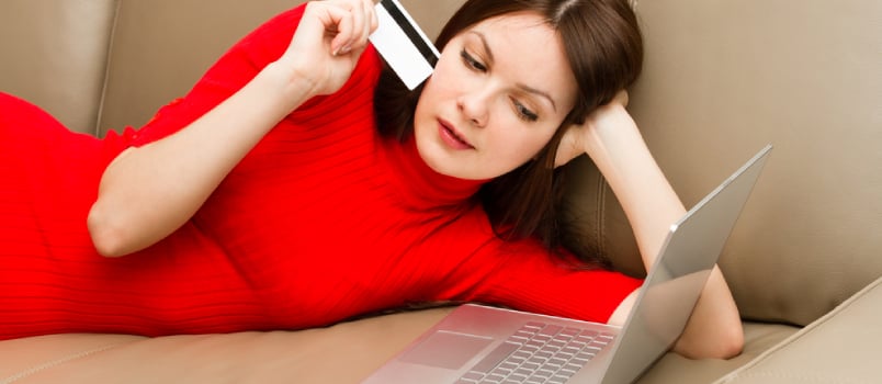 Beautiful Woman Lying on the Sofa With Ultra Thin Laptop and Credit Card.