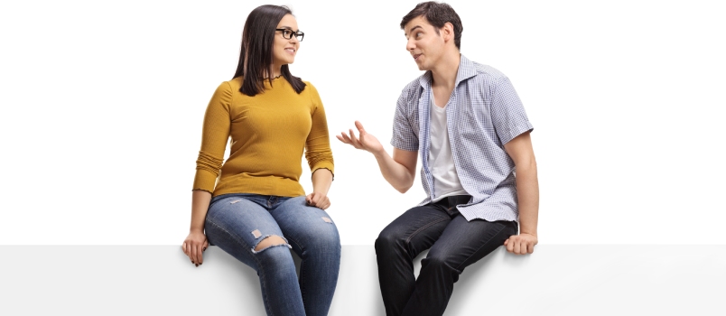 Full Length Shot of a Young Man Sitting on a Blank Signboard and Talking to a Young Woman Isolated on White Background