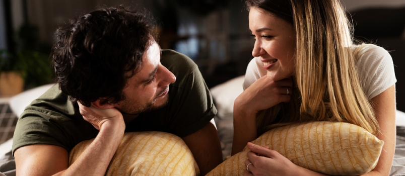 Young Loving Couple Relaxing on Bed Together. Happy Couple Watching Movie at Home.
