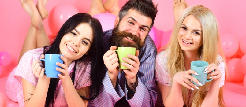 Man and Women in Domestic Clothes, Pajamas. Threesome Relax in Morning With Coffee