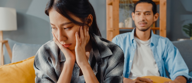 Upset Asian Couple Wife Sit on Couch Listen to Furious Husband Yelling Feel Unhappy Talk Negative to Her.