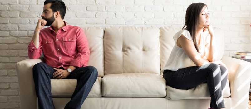Husband and Wife Sitting on the Couch and Not Talking After an Argument at Home. Social Distancing Concept