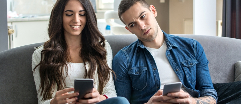 Young Couple Using Smartphones at Home. Jealous Boyfriend Spying His Girlfriend's Phone.