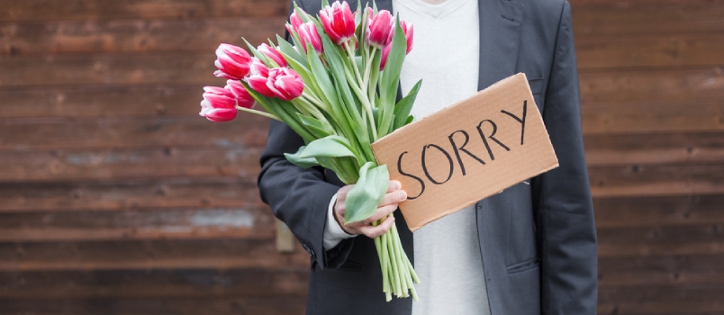 Man Is With Apologizing Card With the Fresh Flowers
