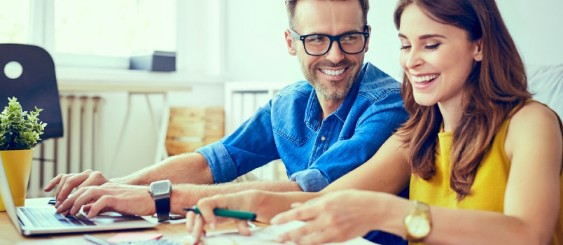 Happy Couple at Home Paying Bills With Laptop