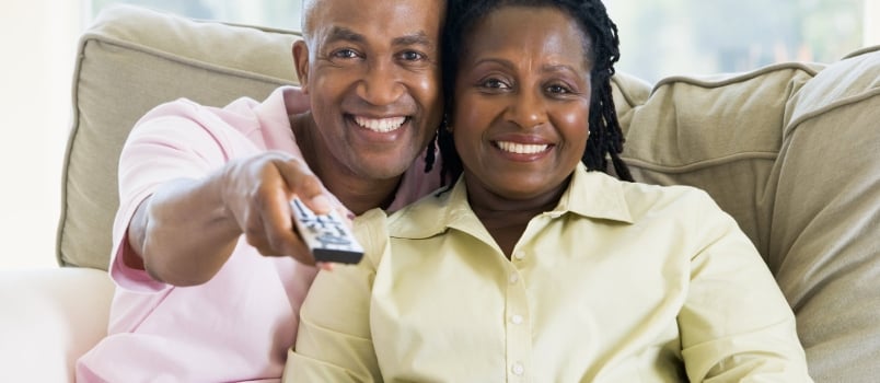 Couple Relaxing in Living Room Holding Remote Control and Smiling