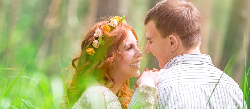 Beautiful Bride and Handsome Groom Sitting on Fresh Green Grass and Talking, Love and Happiness in Wedding Day