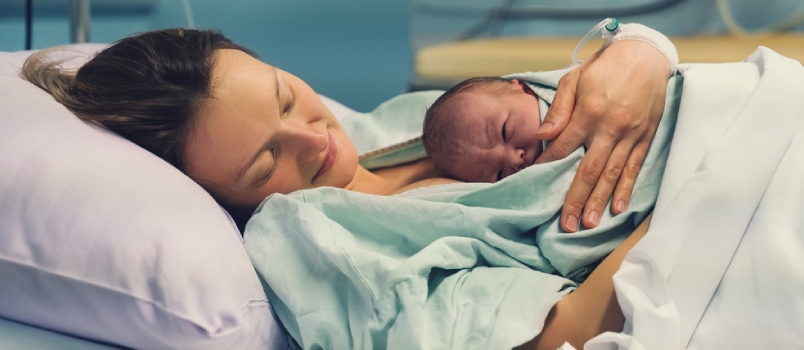 Child Birth in Maternity Hospital. Young Mom Hugging Her Newborn Baby After Delivery