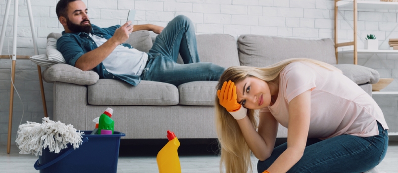 Man Lies on Couch and Typing on Phone, Sad Woman Clings to Her Head and Washes Floors at Home