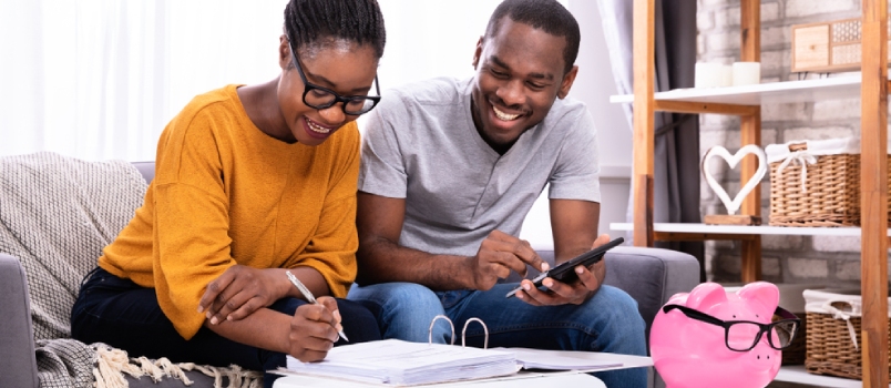 Young African Couple Sitting on Sofa Calculating Invoice