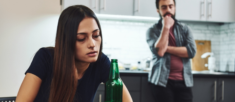 Alcoholic Family Women With the Beer Bottle While Stressed Husband Standing Right Behind Her in the Kitchen