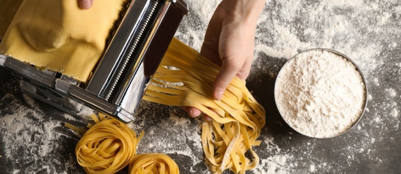 Woman Preparing Noodles With Pasta Maker Machine at Grey Table