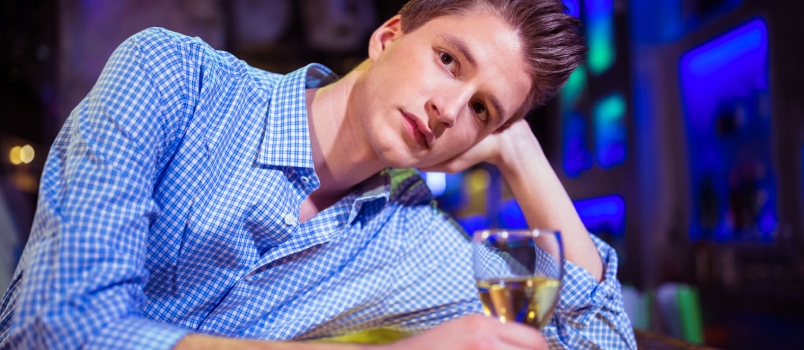 Sad Young Man With Glass of Drink at Bar Counter