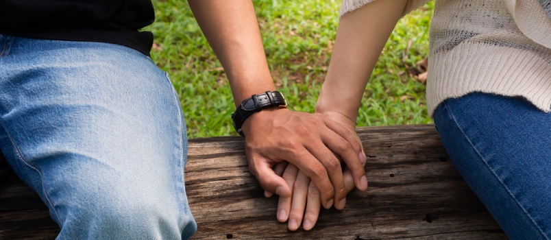 Young Couple Holding Hand While Working or Spending Time Outdoor Plublic Park in Warm Summer Daylight