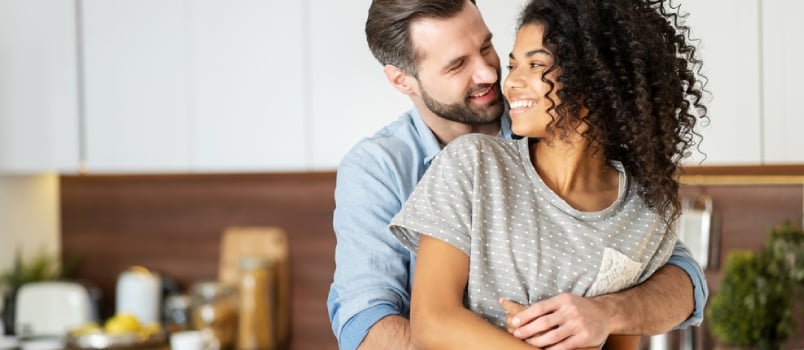 Smiling Man Hugging From Behind Charming African American Woman