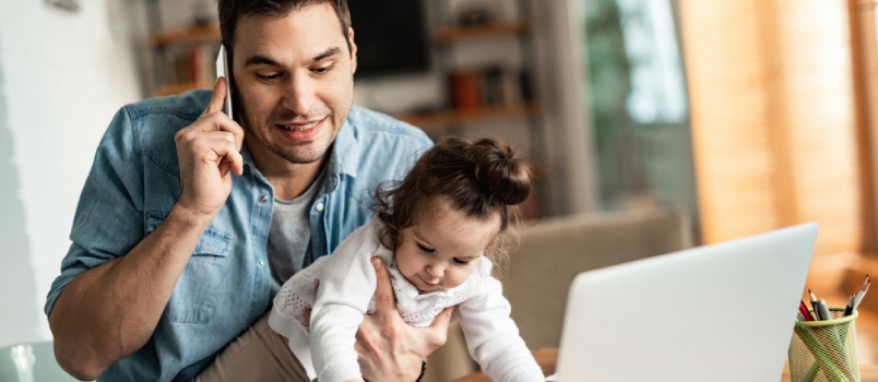 Young Working Father Talking on the Phone While Babysitting His Playful Daughter at Home.