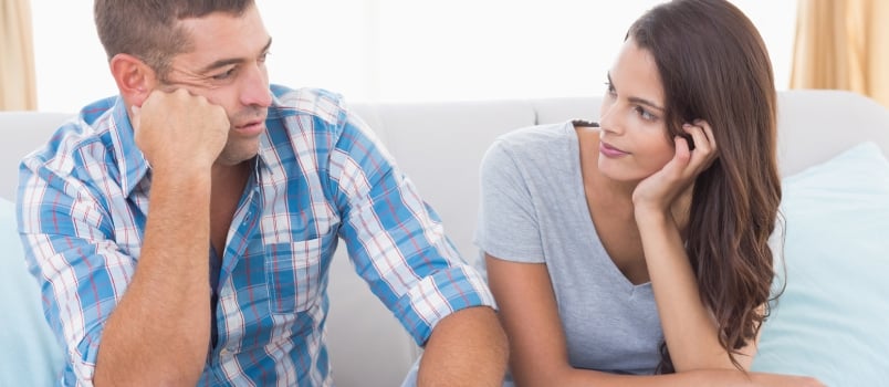 Couple discussing while sitting on sofa at home