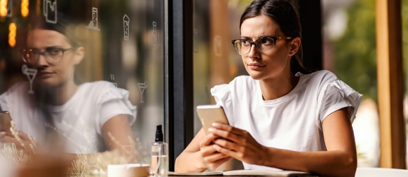 An angry college girl is sitting in a coffee shop and writing messages to someone