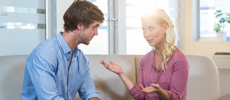 Unsmiling couple talking to each other in the therapist office