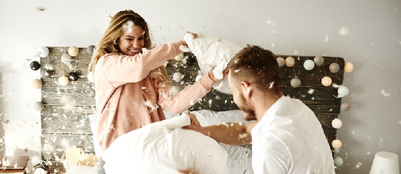 couple playing pillow game at bedroom