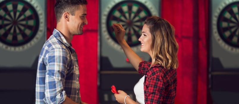 Young Couple Flirting and Playing Darts